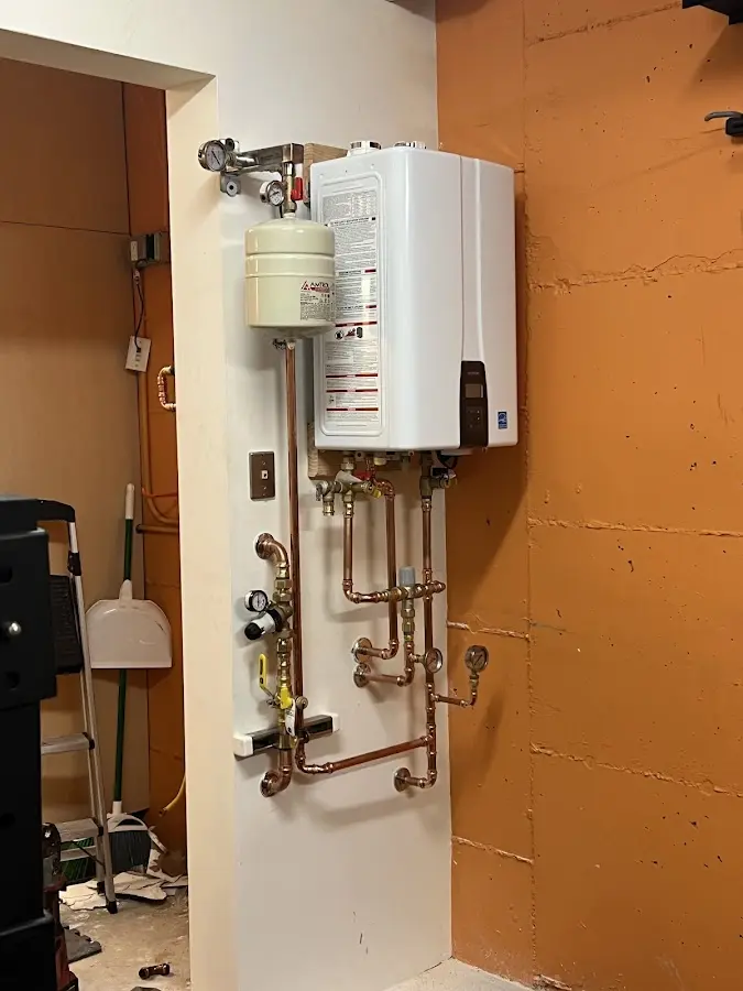 Plumbing technician inspecting water heater connections in Killingworth